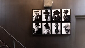 Una escalera con barandillas metálicas que lleva a una pared oscura adornada con fotografías blanco y negro enmarcadas.