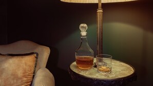 Una mesa con una lámpara, una botella y un vaso.