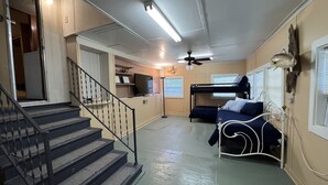 A compact living space with a bunk bed, a kitchenette, and a staircase leading to an upper level.
