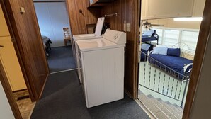 A compact kitchen with a washer and dryer, a small dining area, and a balcony with a bed.