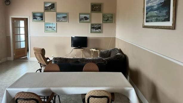 Un área de comedor con una mesa y sillas, un sofá, un televisor y cuadros en la pared.