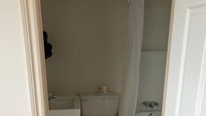 Un baño pequeño y estrecho con inodoro, lavamanos y ducha.