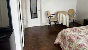 Una habitación de hotel con una cama, dos sillas, una mesita y una puerta.