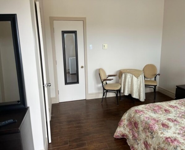 A hotel room with a bed, two chairs, a small table, and a door. - Hôtel Motel de la Minganie (Longue-Pointe-de-Mingan)