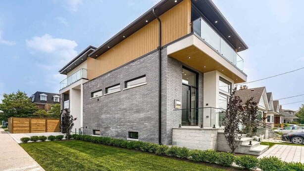 A modern two-story house with a flat roof, large windows, and a mix of brick and wooden exterior walls. - Stylish, spacious, and bright 2-bedroom furnished basement apartment (Toronto)