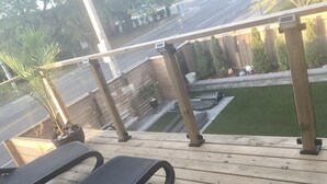 A wooden deck with two lounge chairs, a small planter, and a view of a lawn and fence. - Stylish, spacious, and bright 2-bedroom furnished basement apartment (Toronto)