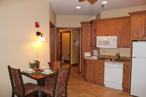 A kitchen with wooden cabinets, a microwave, a dishwasher, and a dining area with a table and chairs.