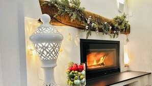 A fireplace with a TV screen, a decorative glass bowl with ornaments, and a white lantern.