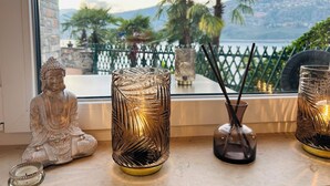 A Buddha statue, two decorative glass vases, and a view of palm trees and mountains through a window.