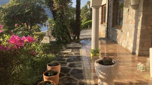 A stone pathway leading to a building with columns and a view of the sea.