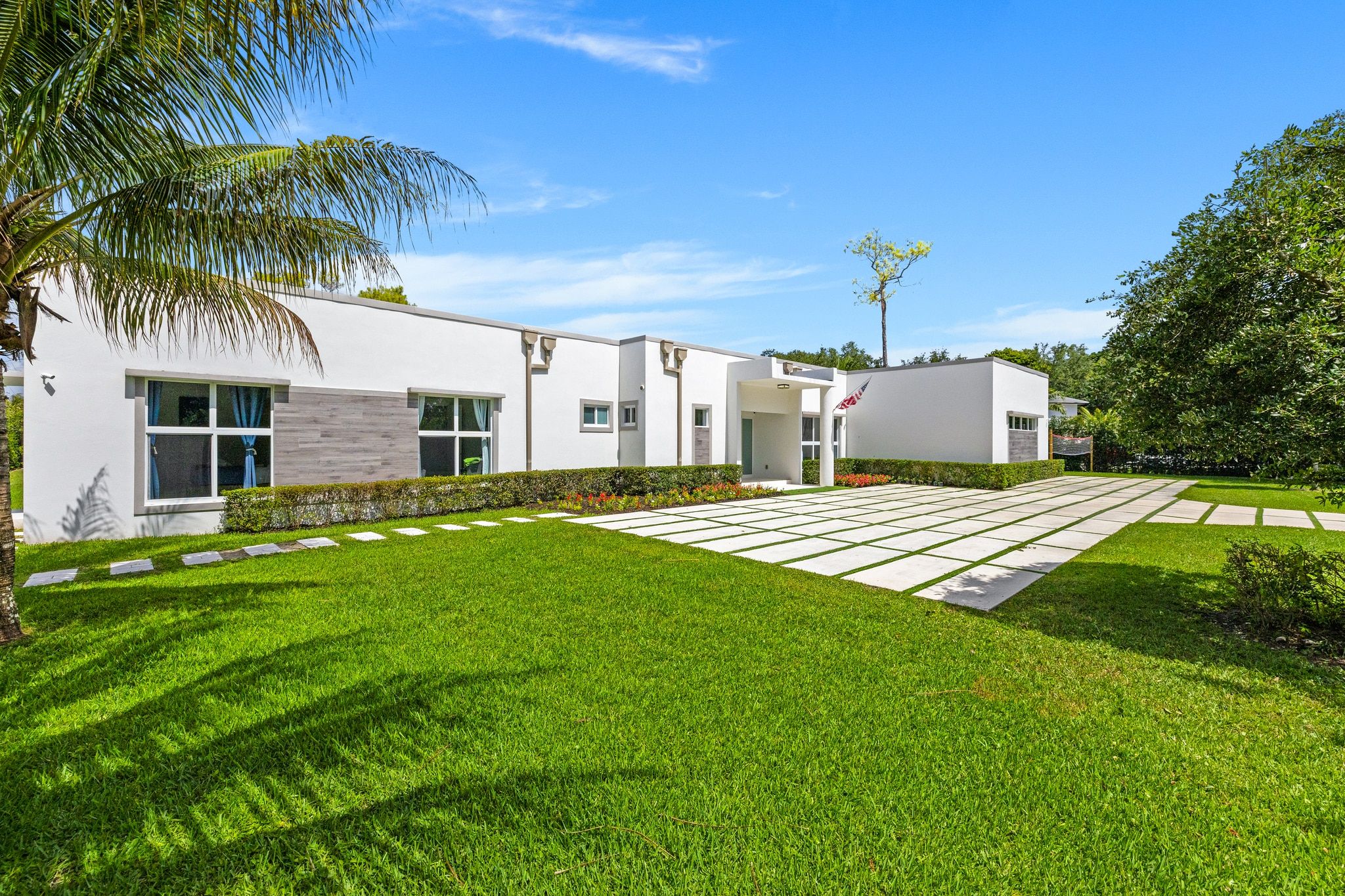 A modern two-story house with a well-maintained lawn and a paved driveway.