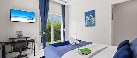 Un dormitorio con cama, escritorio, silla, televisor y un cuadro.