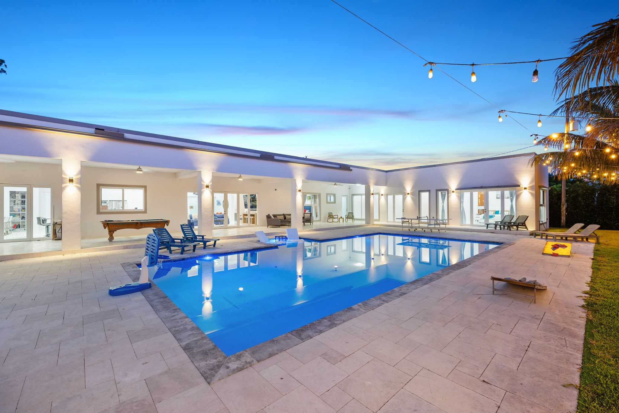 Una piscina con lettini e un tavolo da biliardo in un'ampia area interna.