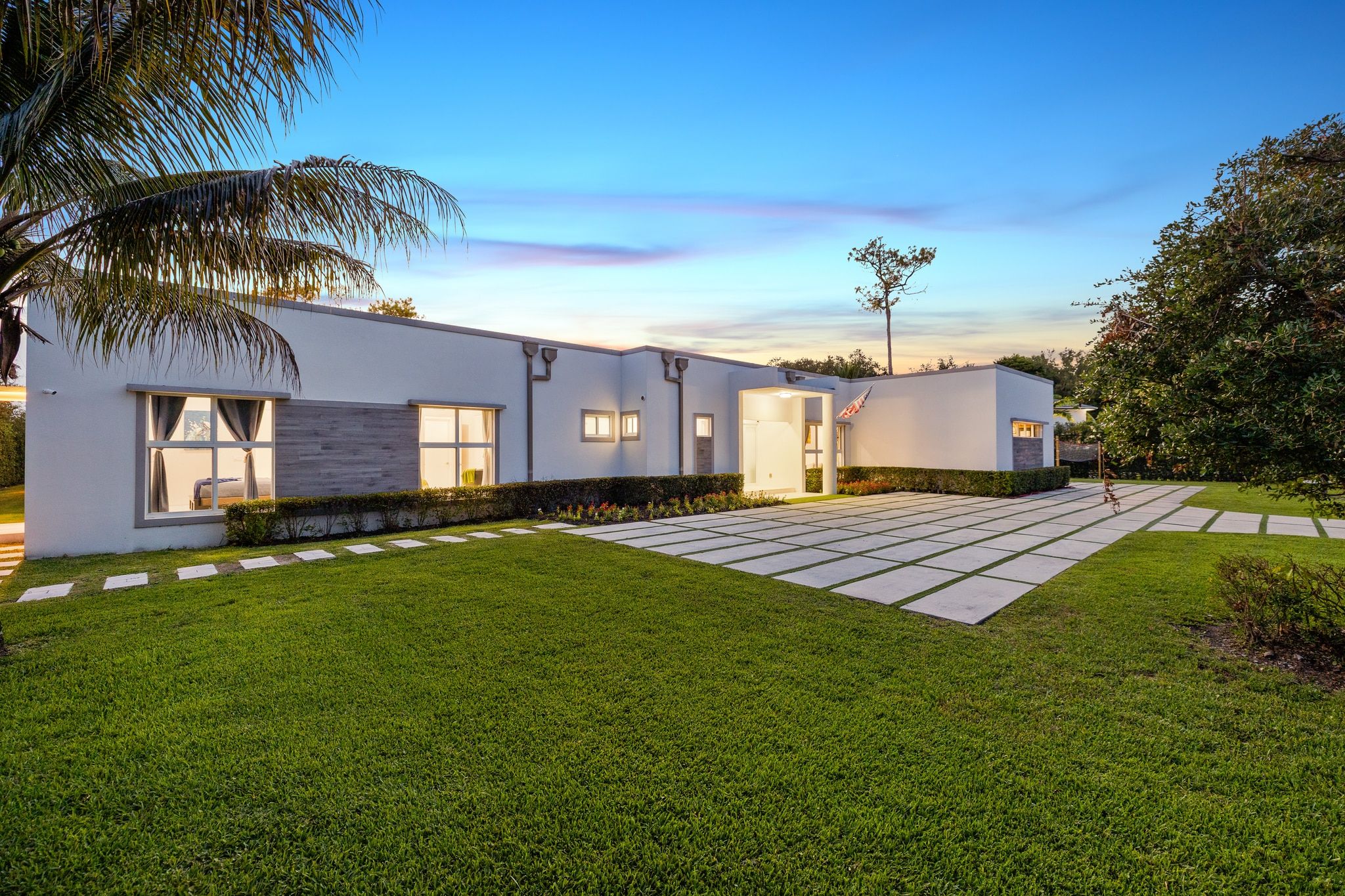 A modern two-story house with a well-maintained lawn and a paved walkway.