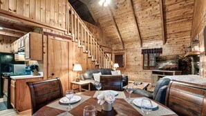 A wooden cabin interior with a dining area, kitchen, and living space. - Cozy Mountain Retreat w/hot tub, 5 mins to downtown strip (Sevierville)
