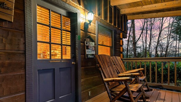 A wooden cabin with a dark door, a rocking chair on the porch, and a sign that says "The Cabin is my Happy Place." - Cozy Mountain Retreat w/hot tub, 5 mins to downtown strip (Sevierville)
