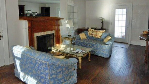 Un salon avec une cheminée, deux canapés à motifs, une table basse et un grand miroir.