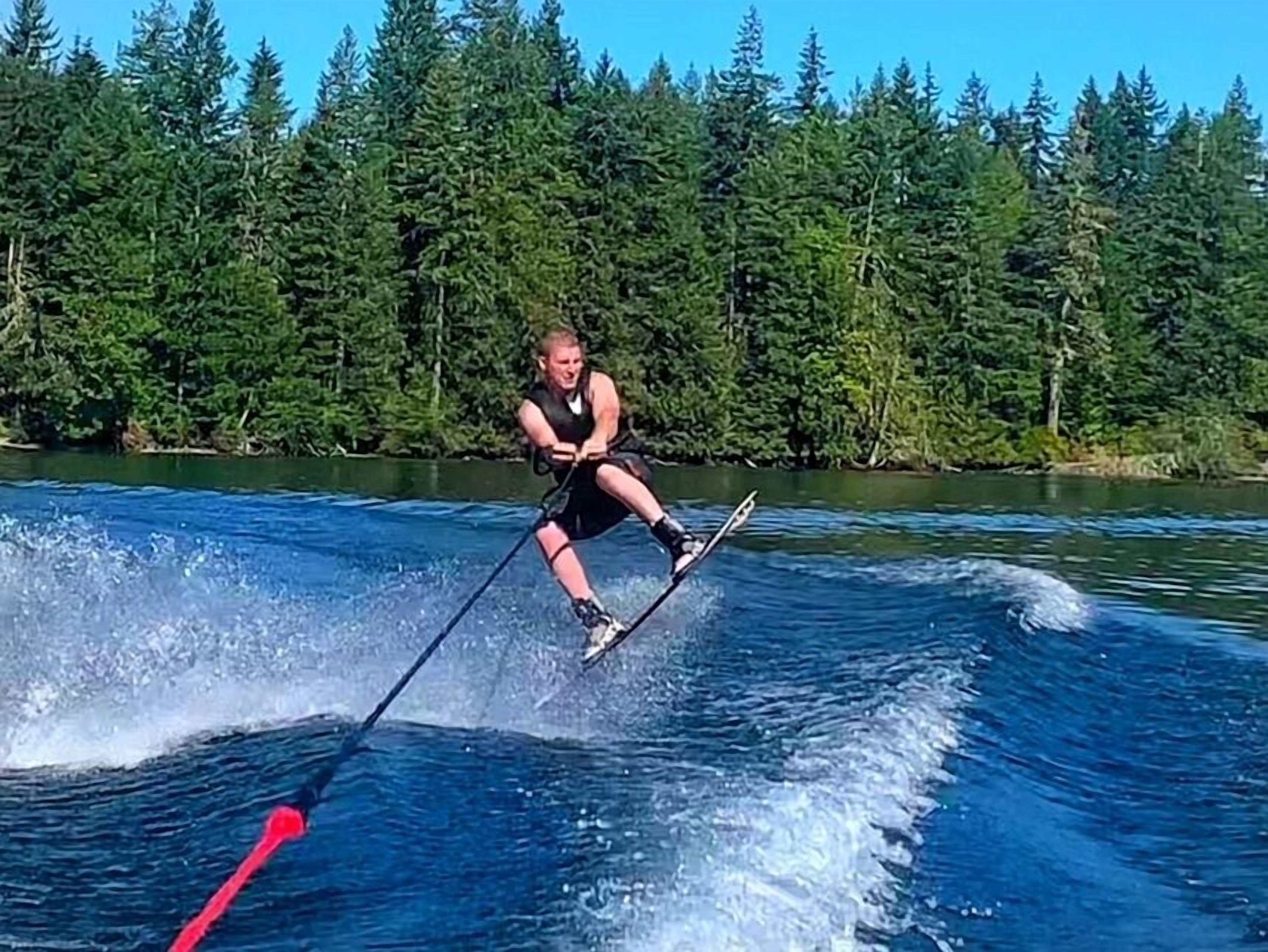 A person water skiing on a lake with a forest in the background.