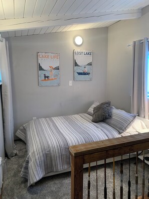 Un dormitorio con una cama, cabecera de madera, una lámpara de pared y dos carteles.