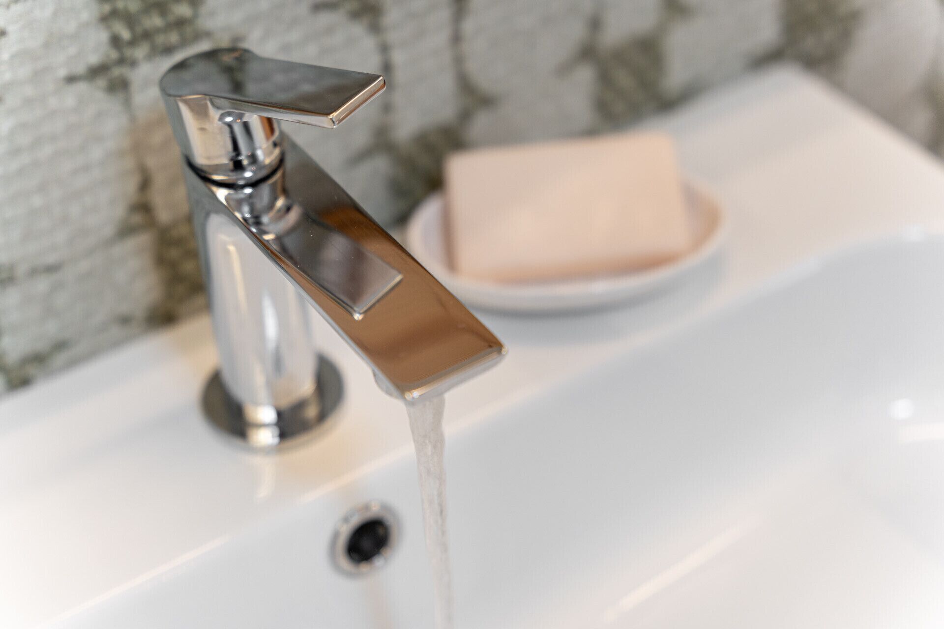 A modern bathroom sink with a chrome faucet and a soap dish.