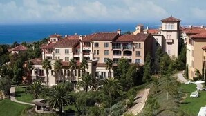 Un hôtel situé sur la côte, composé de plusieurs bâtiments, bordé de palmiers et offrant une vue sur l’océan.
