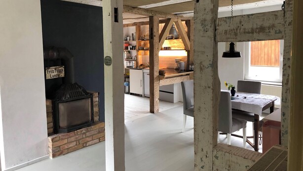 A rustic kitchen with exposed beams, a brick fireplace, and a dining area with a table and chairs. - 5 minutes from the national park Holiday home for hikers, cyclists, anglers (Lunow-Stolzenhagen)