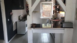 A kitchen with a central island, a stove, and a window overlooking a brick wall. - 5 minutes from the national park Holiday home for hikers, cyclists, anglers (Lunow-Stolzenhagen)