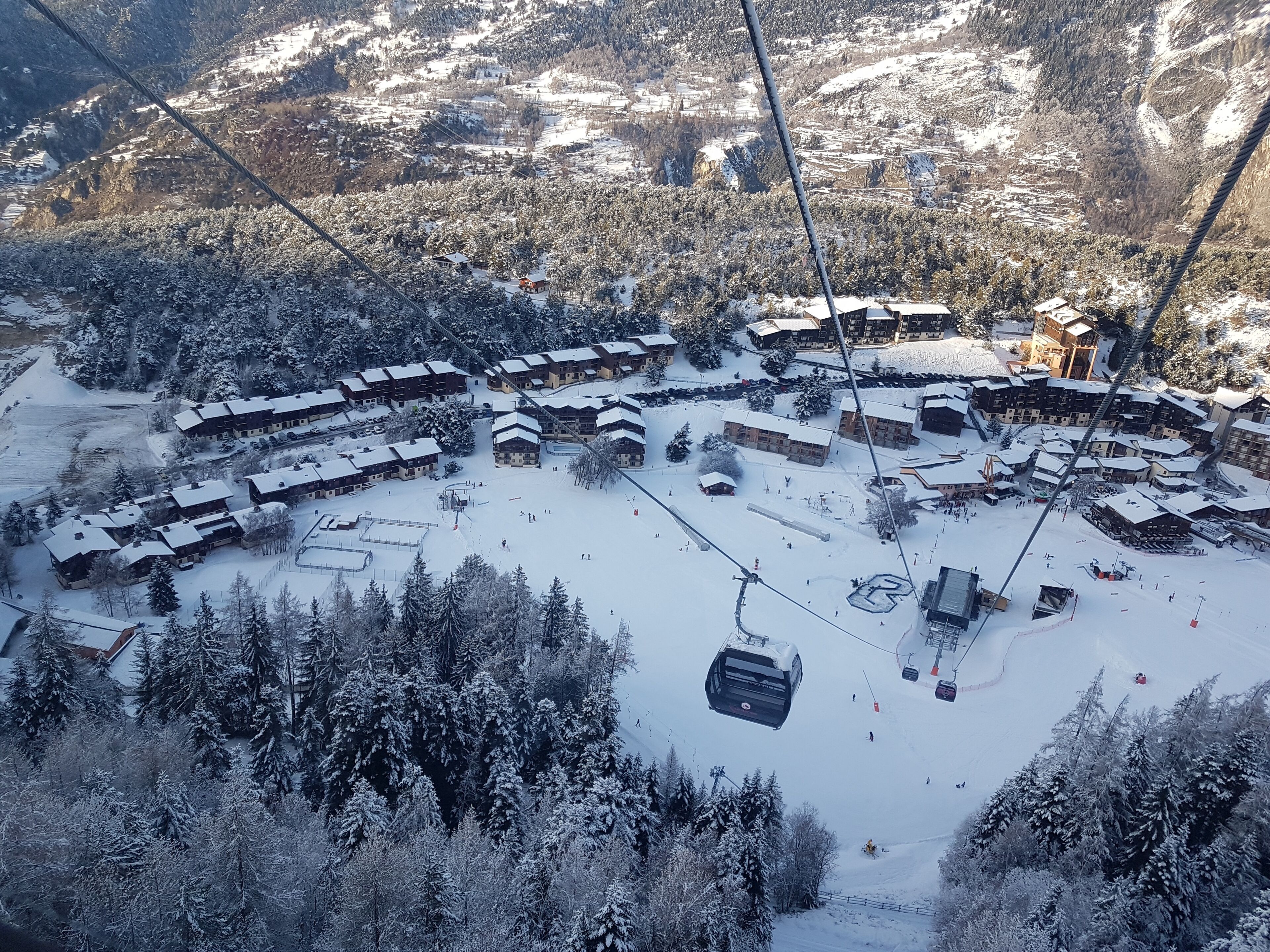 Un centro de esquí cubierto de nieve con varias construcciones tipo chalet, telesillas y una pista de esquí.