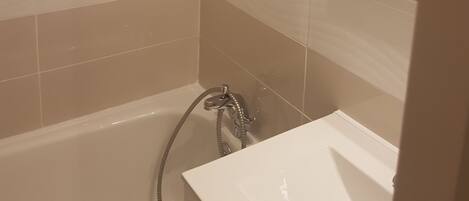 A bathroom with a bathtub, a shower, and a sink.