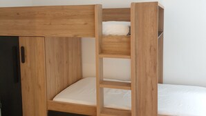 Un llit superposat amb estructura de fusta i un petit armari.