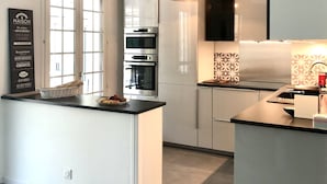 A modern kitchen with white cabinetry, stainless steel appliances, and a central island. - Wonderful place 3* with view and pool (Montesquieu-des-Albères)