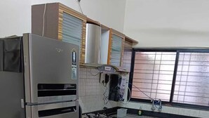 A kitchen with a stainless steel refrigerator, wooden cabinets, a gas stove, and a window with blinds.