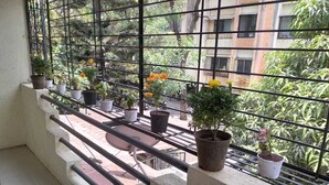 A balcony with potted plants and a metal railing.