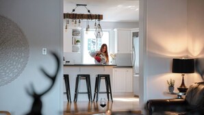 Eine moderne Küche mit weißen Schränken, einer Pendelleuchte und einer Person beim Kochen.