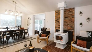 Ein gemütliches Wohnzimmer mit Kamin, einem Essbereich mit Tisch und Stühlen sowie Blick ins Freie.