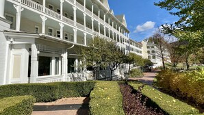 A multi-story hotel with a symmetrical facade, multiple balconies, and a well-maintained garden with hedges and a pathway. - Whispering Pines Retreat-Newly Renovated Countryside Home (Bedford)