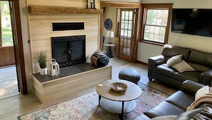A living room with a fireplace, a ceiling fan, a television, a sofa, and a coffee table. - Whispering Pines Retreat-Newly Renovated Countryside Home (Bedford)
