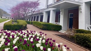 A building with a brick facade, white columns, and a covered walkway. - Whispering Pines Retreat-Newly Renovated Countryside Home (Bedford)