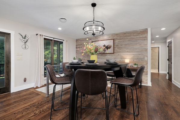 A modern dining area with a round table, six chairs, and a chandelier.