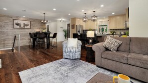 A modern living room with a sofa, armchair, and dining area.