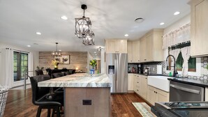 A modern kitchen with a central island, stainless steel appliances, and a dining area with bar stools.