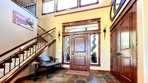 A staircase with stone steps, a wooden bench, a door with glass panels, and a "Welcome to Our Chalet" sign.