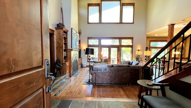 A spacious living area with a stone floor, wooden furniture, and large windows allowing natural light.