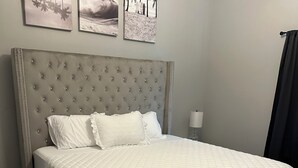 Un dormitorio con una cama grande, cabecera y tres cuadros en la pared.