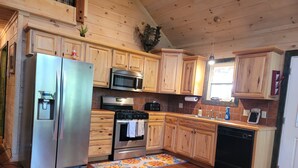 Una cocina con armarios de madera, electrodomésticos de acero inoxidable y piso de madera.