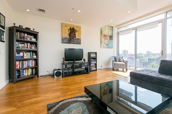 Relax in a spacious living area with a large flat-screen TV, comfortable sofa, and city views.