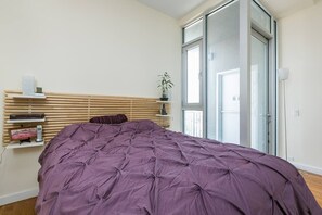 Relax in this serene bedroom with a large bed, wooden headboard, and sliding door to a balcony with a view.