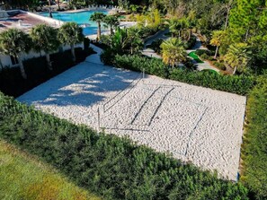 A beach area with a pool and lounge chairs.