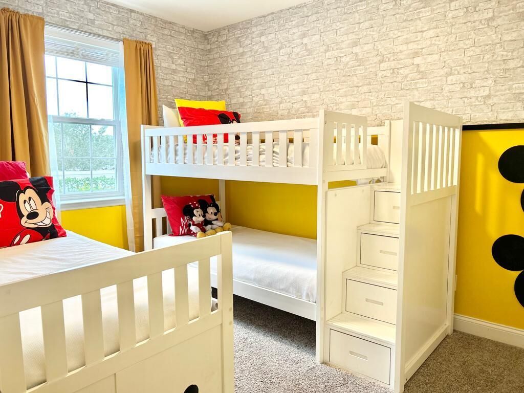 A child's bedroom with bunk beds, a window with curtains, and a brick wall.