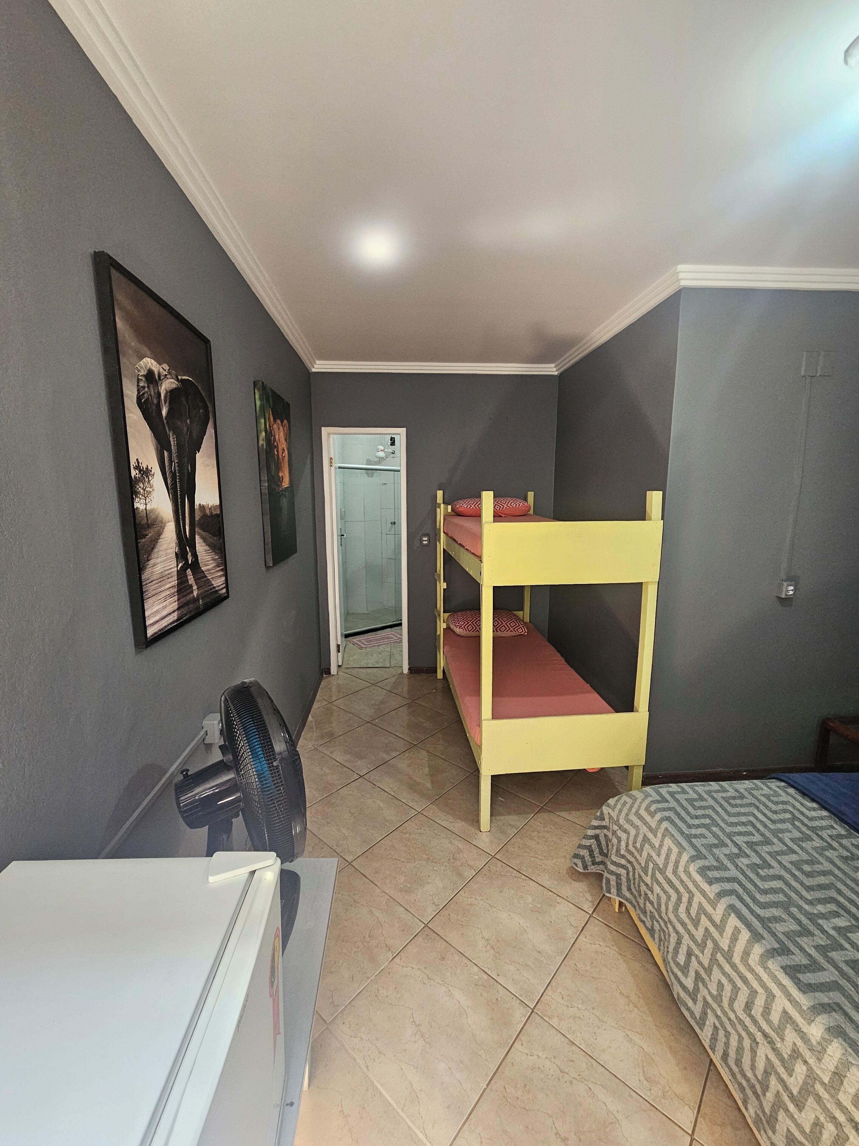 Un dormitorio con literas, un escritorio pequeño y un refrigerador.